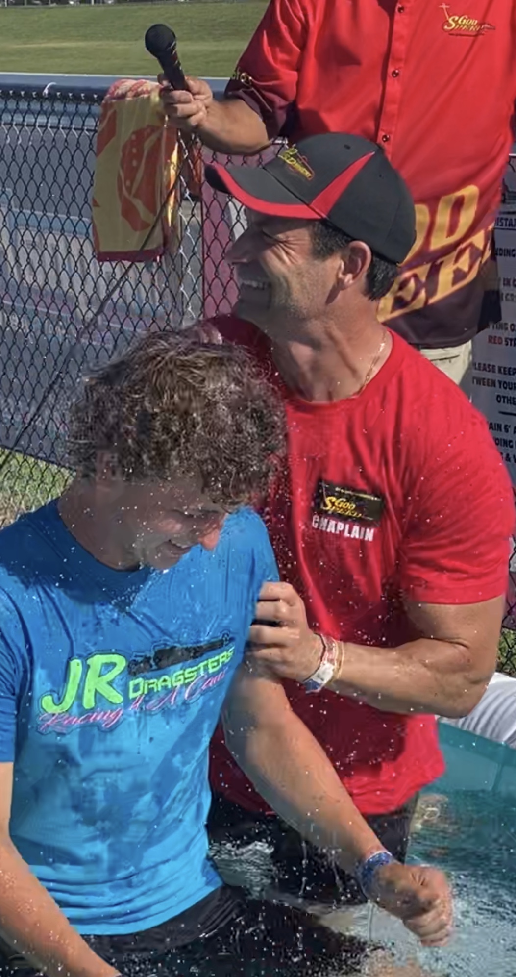 Man baptizing another in outdoor ceremony