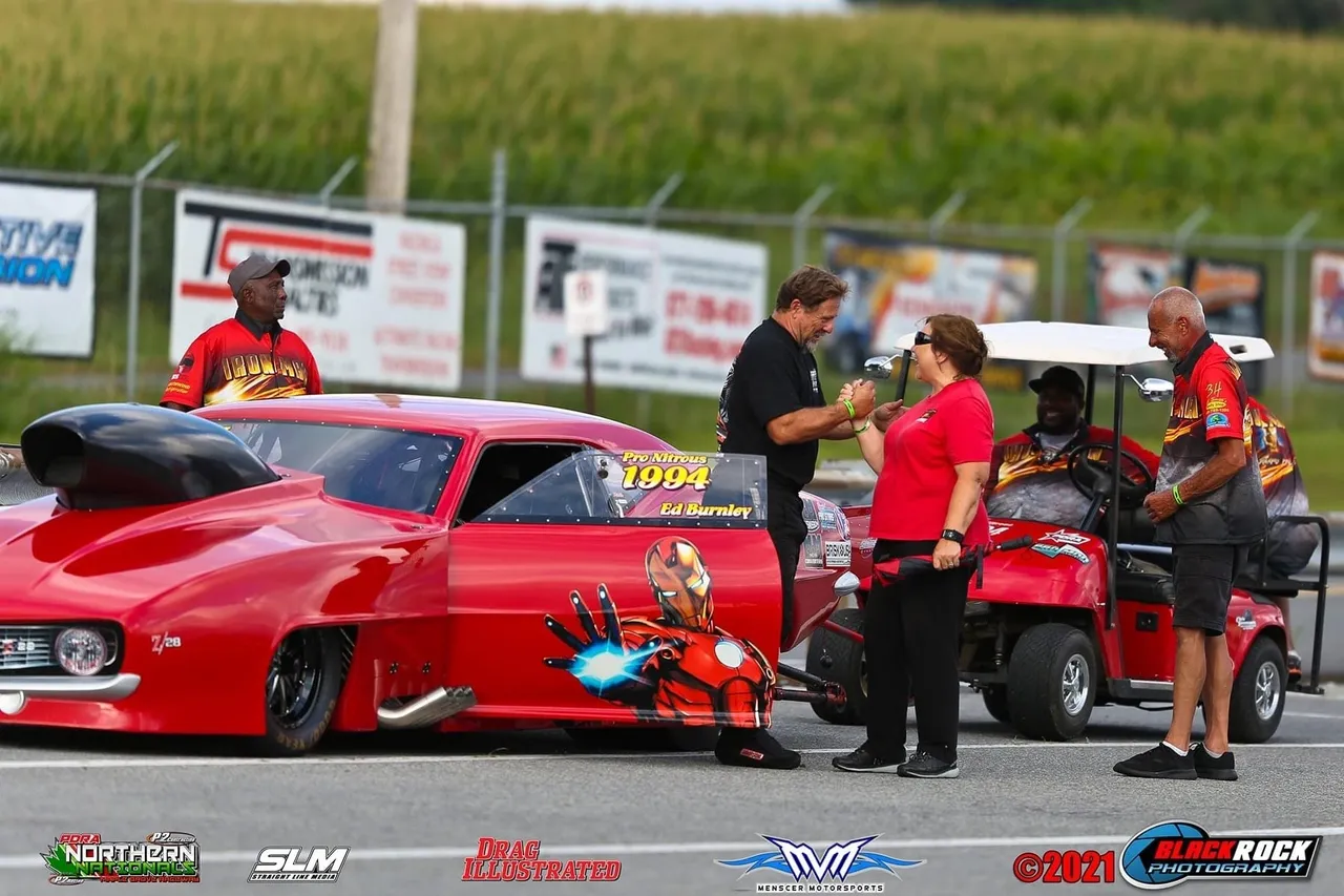 Red drag racing car with group nearby